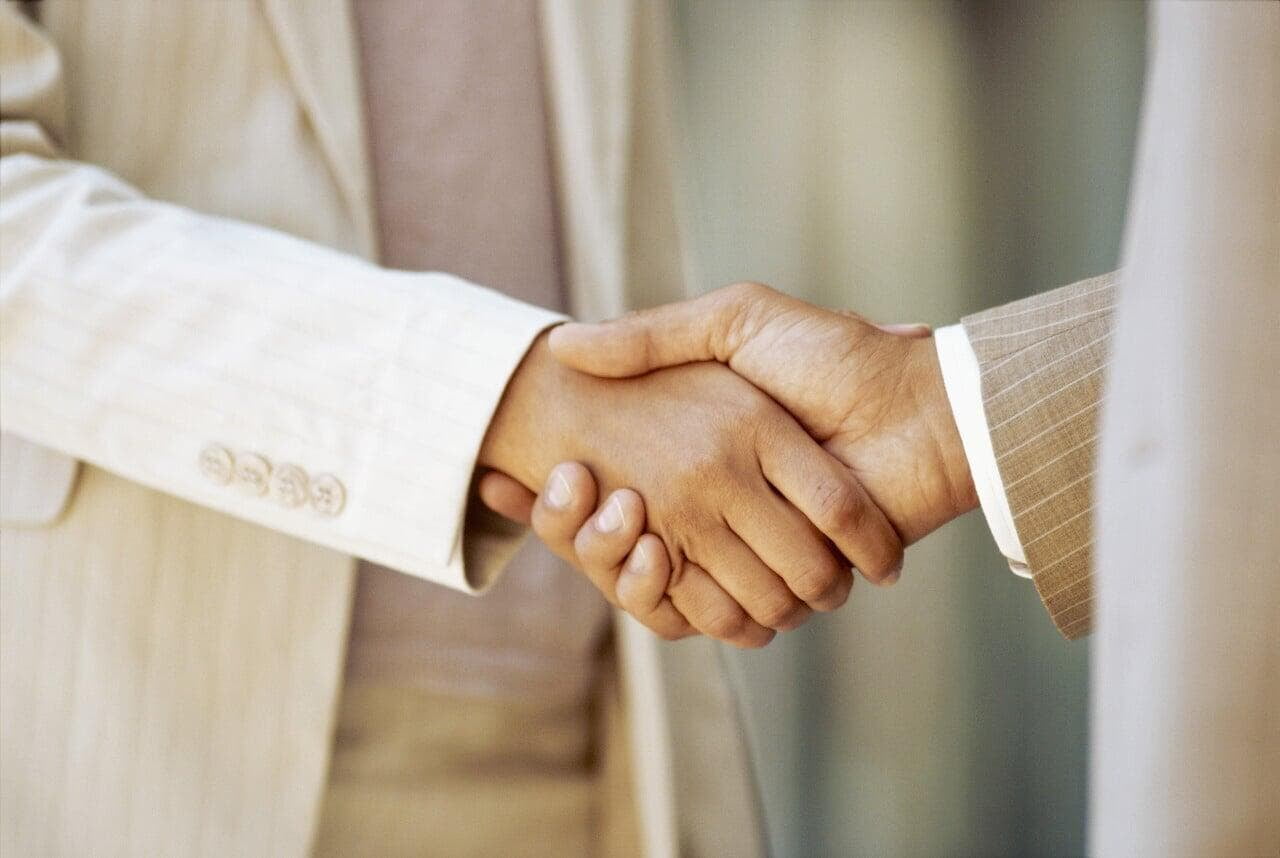 Professional handshake between two people in business attire shows partnership and agreement.